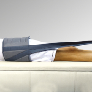 A person lies on a bed wearing a brace on their lower back